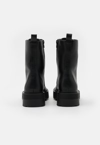 Botas de tobillo de cuero negro con un acabado texturizado, punta redondeada, cremalleras laterales y suelas de goma gruesas y resistentes.