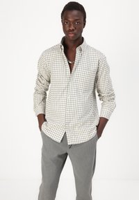 Lange mouw geruite blouse in gebroken wit en grijstinten met een button-down kraag en een enkele borstzak, gecombineerd met grijze broek.