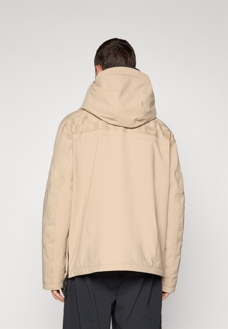 Veste à capuche beige avec une finition mate, présentant des détails superposés sur les épaules et des aérations zippées sur les côtés pour la ventilation.