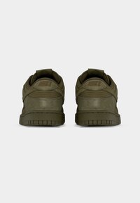 Ζευγάρι αθλητικών παπουτσιών Nike σε ελιά πράσινο, εμφανισμένα από πίσω, με υφή στη μεσαία σόλα και κεντημένα λογότυπα Nike στις φτέρνες.