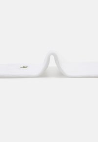Toalla blanca con una textura suave, que presenta un logo verde bordado en un lado, doblada en forma curva.