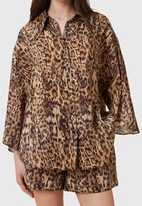 Chemise surdimensionnée à imprimé léopard avec un col à revers, une patte de boutonnage sur le devant et des manches longueur coude, confectionnée dans un tissu léger.