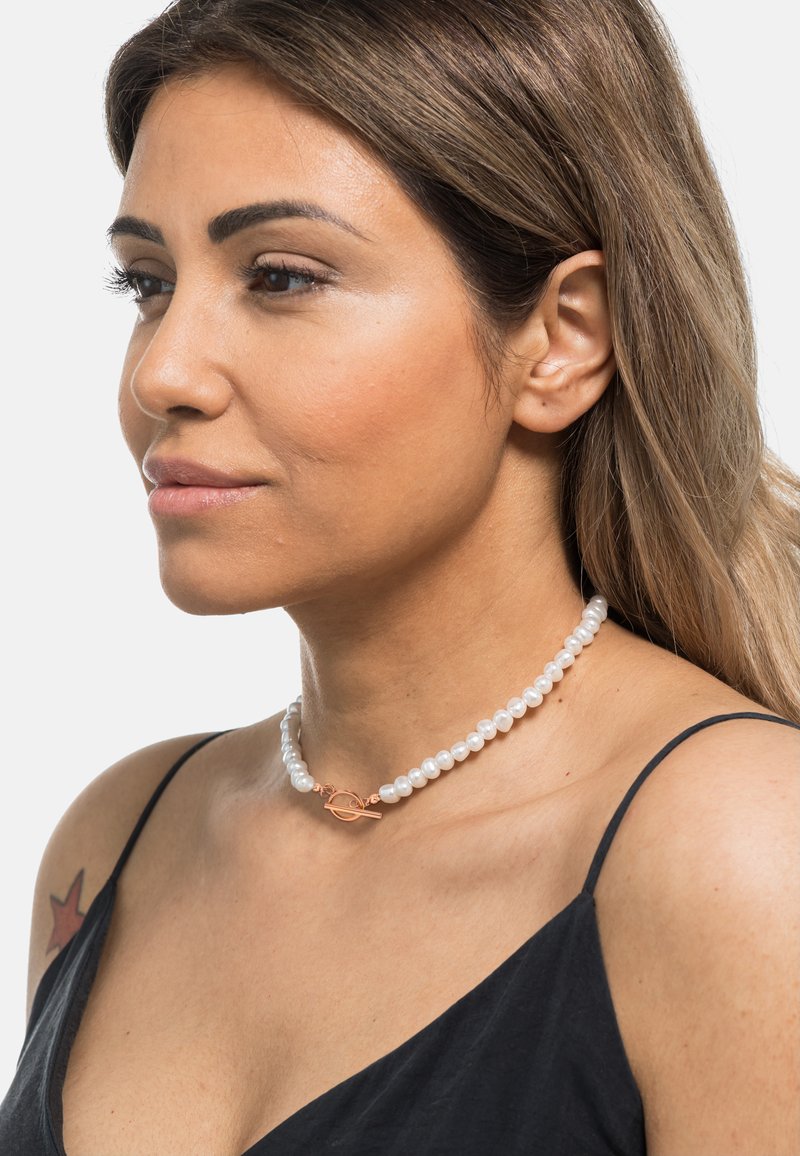 Collana choker in perle che presenta perle irregolari bianche con una chiusura a toggle in oro rosa, offrendo un design sofisticato e dalla texture elegante.