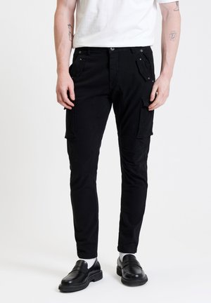 Pantaloni cargo neri realizzati in tessuto resistente, dotati di molteplici tasche e con un design slim fit. Abbinati a scarpe nere senza lacci e calze bianche.
