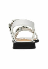 Sandalias blancas con una parte superior de cuero suave, que cuentan con correas anchas y una suela de goma negra. Los detalles notables incluyen acentos de hardware en plata.