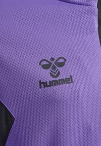Lila texturerad tyg med en svart logotyp av en bi och ordet "hummel". Designen inkluderar en svart accent på ena sidan.