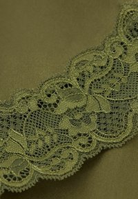 Olivgrön tyg med intrikata spetsdetaljer med blommönster, som visar på fin detaljeringsgrad och en texturerad yta.