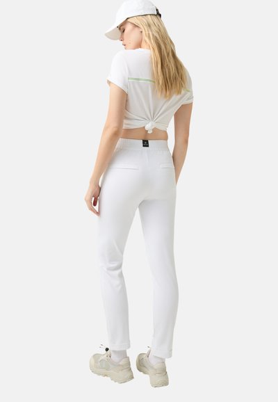 White cropped t-shirt with a knot at the back and green accent, paired with white fitted pants featuring back pockets and elastic waistband.