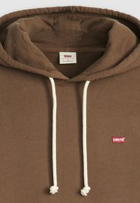 Felpa marrone con cordini, caratterizzata da un piccolo logo rosso di Levi's posizionato sul lato sinistro del petto. Realizzata in un morbido tessuto testurizzato con una vestibilità standard.
