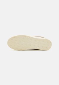 Beige sneaker såle med en teksturert, mønstrete gripeflate; lysfarget gummimateriale; avrundet form med en jevn kant.
