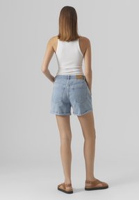 Shorts in denim azzurro chiaro con un taglio classico, risvolti, due tasche posteriori e una etichetta in pelle beige sulla parte posteriore della vita.