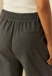 Pantaloni felpati grigi, con una cintura elastica e una piccola tasca posteriore piatta. Il tessuto appare morbido e leggermente elasticizzato.