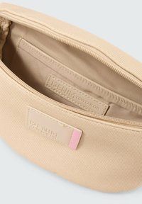 Beige ritssluiting pouch gemaakt van gestructureerde stof, met een eenvoudig ontwerp, een binnenvak en een klein roze accentlabel.
