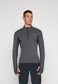 Long-sleeve athletic top in dark grey, featuring a half-zip neck and thumbholes. Made from textured, breathable fabric with contrasting sleeves.