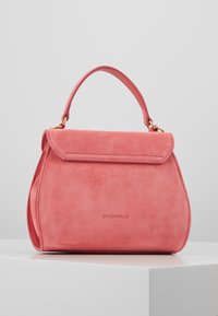 Sac à main en daim rose avec une forme structurée, une poignée supérieure et une fermeture par rabat. Il présente des accessoires en or et un logo en relief à l'avant.