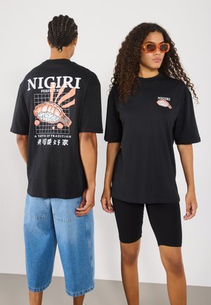 Black t-shirts with "NIGIRI" graphic; one features a shrimp design. The male model wears distressed denim shorts; the female wears black bike shorts.