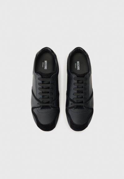 Black sneakers featuring a mix of smooth leather and suede, with a round toe, tonal laces, and contrasting textured accents on the upper.