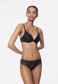 Zwarte kant bralette en doorschijnende slipjes met scalloped randen, geometrische patronen en textuurstof voor extra detail en complexiteit.