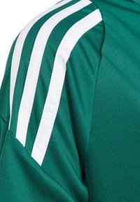 Camiseta deportiva verde con rayas verticales blancas en los hombros. Hecha de un tejido transpirable, con una textura suave y un ajuste estructurado.