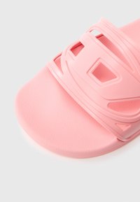 Ružová gumená šľapka so štruktúrovanou podrážkou a výrazným dizajnom remienka s výrezmi. Hladký, mäkký povrch zvyšuje pohodlie.