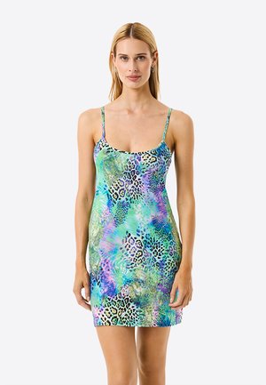 Mujer que lleva un vestido mini sin mangas, ajustado, con tirantes finos, con un estampado animal colorido en azul, verde y morado.
