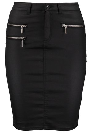 Mujer que lleva una chaqueta roja de cuero, top de encaje gris, falda lápiz negra, medias, botines y sostiene un bolso de mano negro.