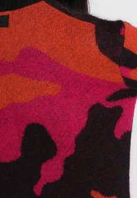 Maglione lavorato a maglia con motivo camouflage in tonalità di rosa, arancione e nero. Texture morbida e scollo rotondo.