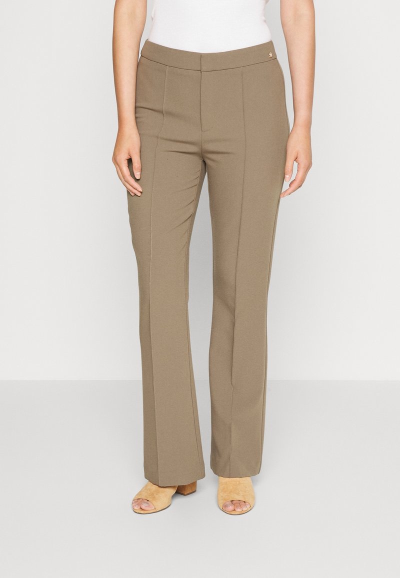 Pantaloni beige su misura con design a gamba dritta, caratterizzati da cuciture frontali e una vita piatta. Abbinati a sandali con tacco marroni chiari.