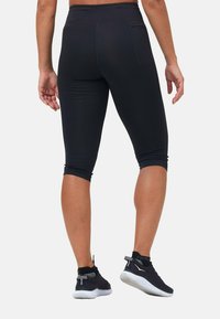 Schwarze Capri-Leggings mit glatter Textur und elastischem Bund, ausgestattet mit einer Gesäßtasche und knöchellangen Abschlüssen.