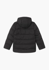 Doudoune noire avec capuche, présentant un design matelassé, une texture lisse et un détail de logo au bas.