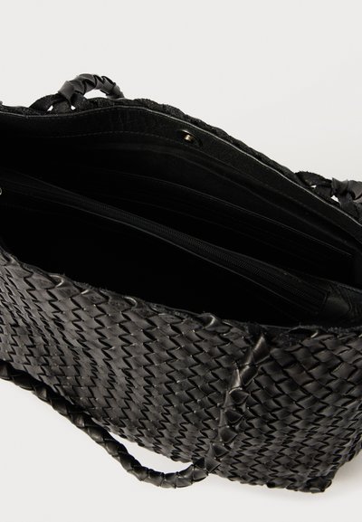 Μαύρη πλεγμένη τσάντα χειρός με υφασμάτινη επιφάνεια και πλεκτές λαβές. Διαθέτει ανοιχτό επάνω μέρος, ευρύχωρο εσωτερικό και πολλαπλές θήκες.