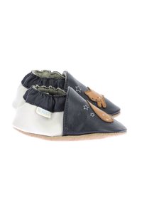 Scarpe slip-on in pelle bianco e nero, con applicazione di orso, caviglia elasticizzata e accenti a stella su una suola flessibile.