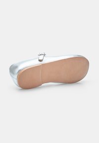 Scarpa metallica argento con superficie liscia, punta arrotondata e una piccola fibbia di lato. Presenta una suola in gomma testurizzata marrone.