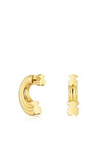 Boucles d'oreilles en métal doré mettant en avant un design ondulé avec des accents floraux. Texture lisse avec finition brillante, présentant des formes modernes et élégantes.