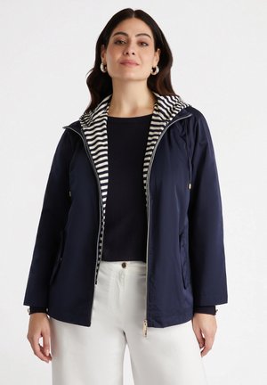 Giacca leggera blu navy con fodera a righe nel cappuccio, zip frontale, tasche laterali e polsini a coste. Texture liscia e design casual.