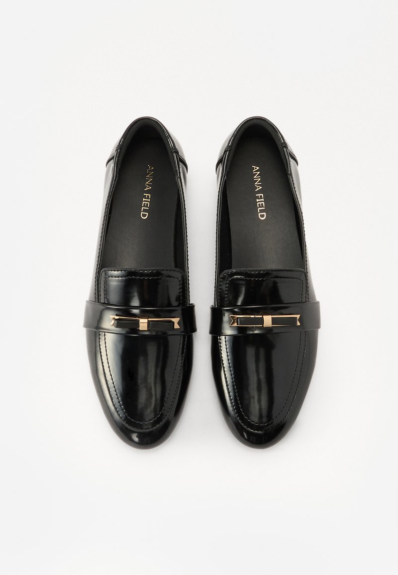 Schwarze Lackleder Slipper mit runder Zehenform, ausgestattet mit einem goldfarbenen Akzent und gestickten Details entlang der Kanten. Flache Sohlen.