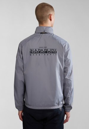 Grijze windjack met een hoge kraag, elastische manchetten en tailleband. Heeft een opvallend zwart logo op de achterkant. Lichtgewicht, gladde textuur.