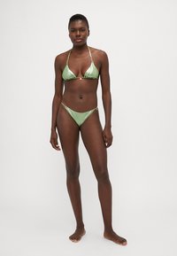 Bikini verde din satin cu top triangular și bretele subțiri, având accente din aliaj de aur și un fund Brazilian. Textură netedă.
