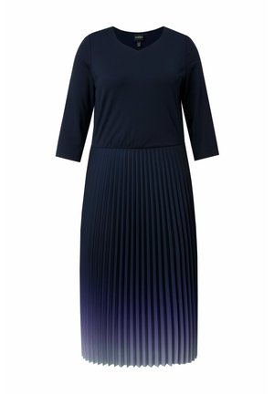 Laivastonsininen mekko, jossa kolme neljänneksen mittaiset hihat, V-aukko, istuva vyötärö ja laskostettu helma, joka haalistuu pohjasta vaaleamman violetiksi.