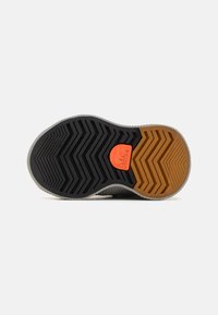 Sneakersula med ett fiskbensmönster. Har svart, grå och orange gummi; orange logotyp nära hälen; texturerad för grepp.