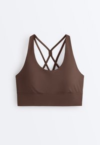 Brassière de sport marron avec larges bretelles frontales et fines bretelles croisées à l'arrière, conçue pour un bon maintien sportif et un confort optimal.