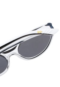 Naočale s sjajnim srebrnim okvirom, crnim lećama i jedinstvenim krilatim detaljima. Neki detalji imaju zlatni trokutasti logo sa strane.