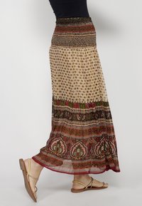 Maxi skirt in lightweight fabric, featuring a smocked waist, intricate floral patterns in red, green, and beige, and a layered design.