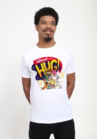 Hvid t-shirt med et farverigt grafisk design, der har teksten "GROUP HUG!" og tegneseriefigurer, herunder dyr og mennesker.