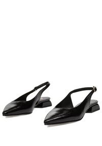 Zapatos de piel negra con tiras traseras, puntera puntiaguda, tacón bajo y diseño cortado. Cuenta con una correa ajustable con hebilla metálica.