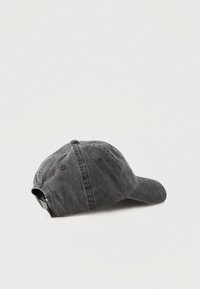 Worn black washed cotton baseball cap with adjustable strap laid flat on a light gray surface.