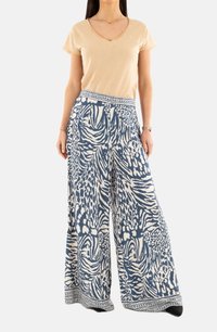 Pantaloni a gamba larga in blu e bianco, caratterizzati da una vivace stampa animale e una vita decorata. Abbinati a una t-shirt beige a scollo a V.