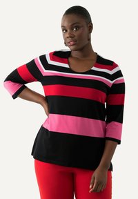 Schwarz-rot gestreiftes Langarmoberteil mit pinken Akzenten; Rundhalsausschnitt. Kombiniert mit roten Hosen, die ein lässiges Design zeigen.