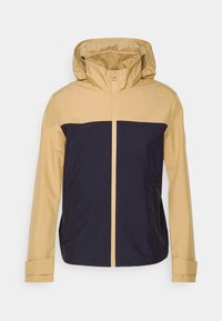 Vandafvisende jakke med en beige overdel og en marineblå underdel, med hætte, frontlynlås og to sidelommer.