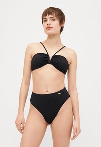 Black bikini set with textured fabric; the top has a twisted design with thin straps, and the high-waisted bottom features a small gold accent.